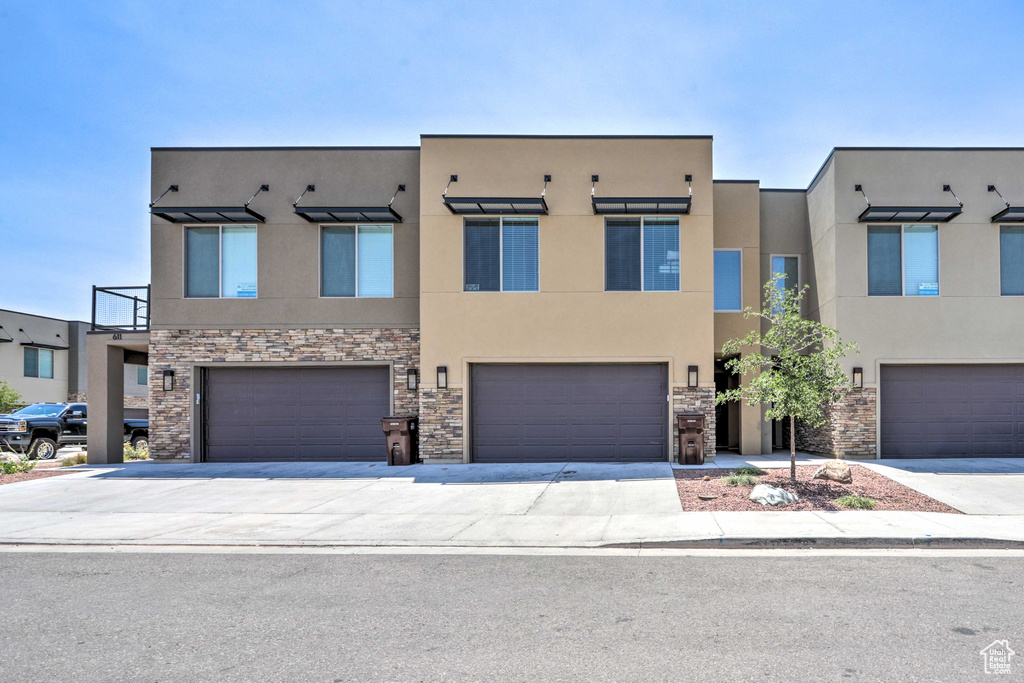 View of property featuring stucco siding, stone siding, and an attached garage