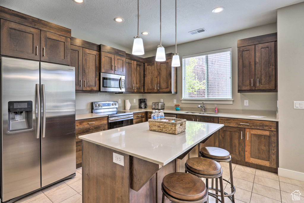 Kitchen with stainless steel appliances, light tile patterned floors, a sink, dark brown cabinets, and recessed lighting