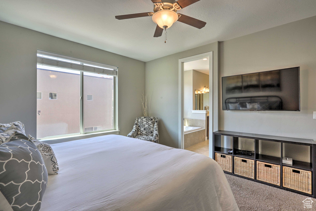 Bedroom featuring a ceiling fan, ensuite bath, and carpet flooring