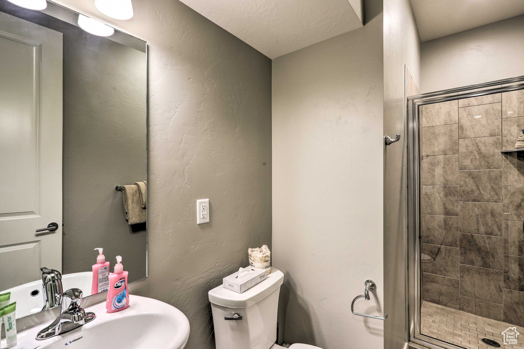 Bathroom featuring toilet, a stall shower, and a sink