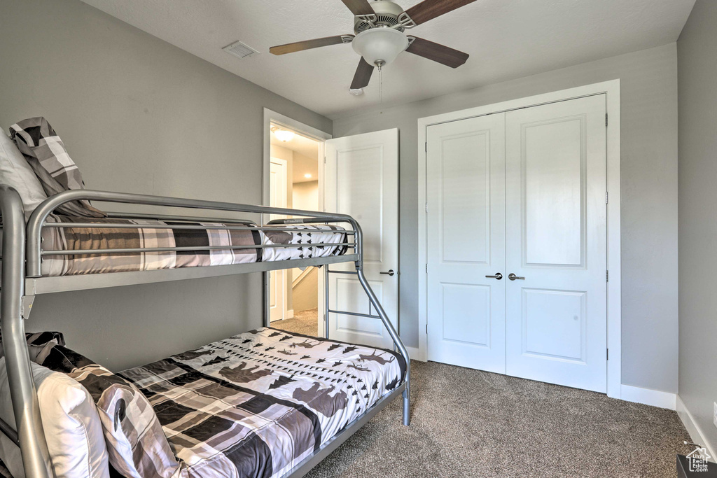 Carpeted bedroom with a closet, baseboards, and ceiling fan