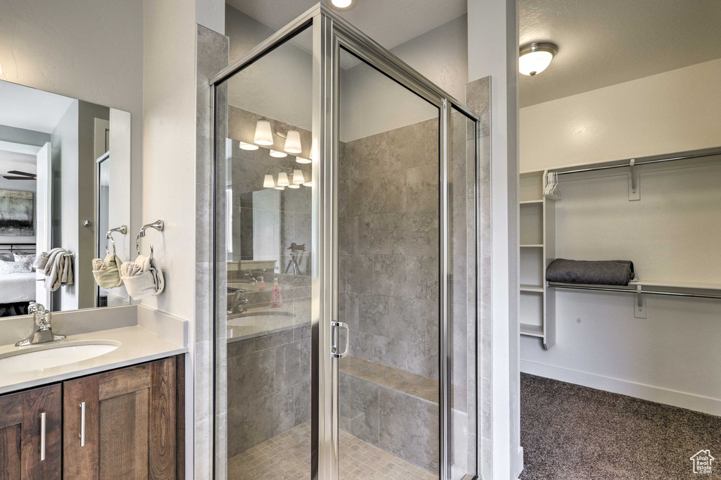 Bathroom with vanity, a spacious closet, and a shower stall
