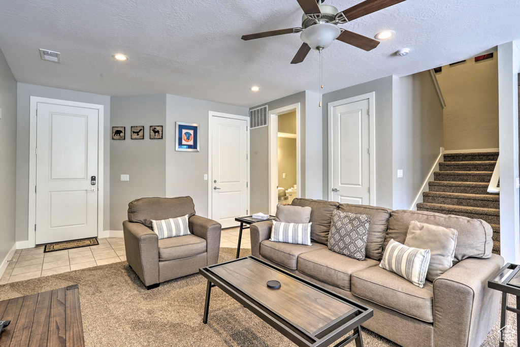 Living room featuring stairs, baseboards, ceiling fan, a textured ceiling, and recessed lighting