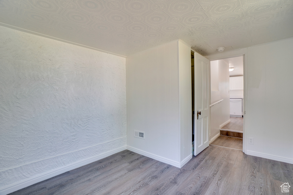 Empty room featuring wood finished floors, an ornate ceiling, and a smoke detector