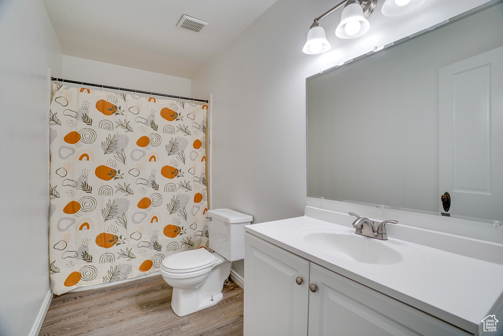 Full bath with wood finished floors, vanity, and curtained shower