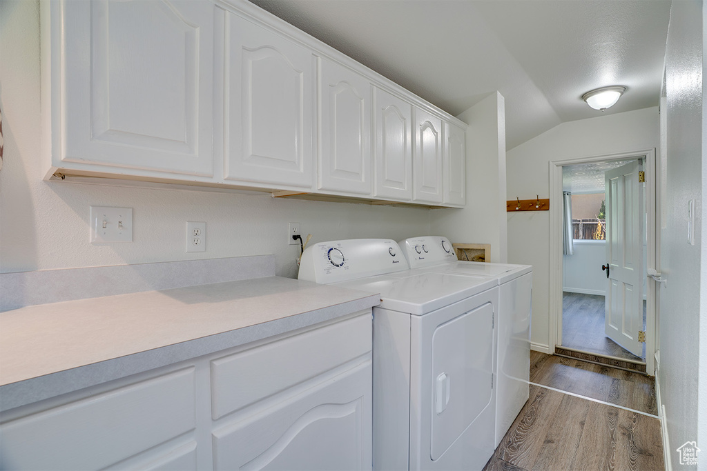Laundry room featuring dark wood-style floors, independent washer and dryer, and cabinet space
