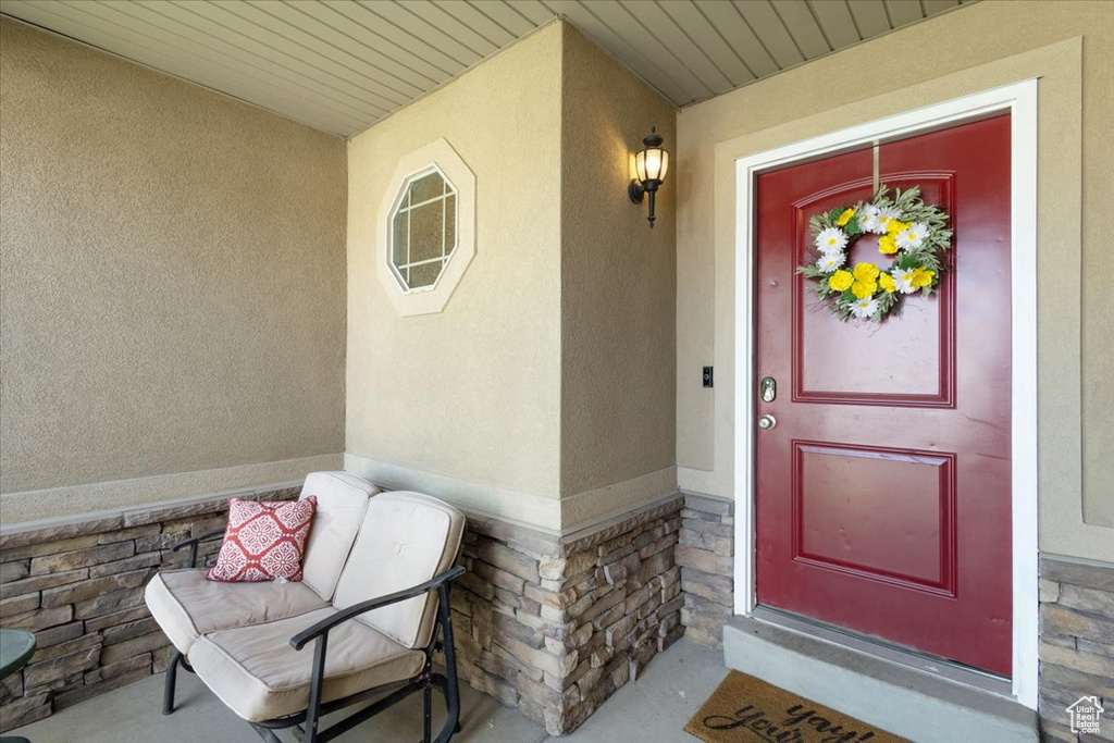 View of exterior entry with stone siding, stucco siding, and a porch