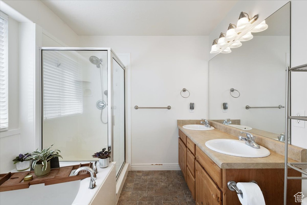 Bathroom with a shower stall, double vanity, a tub to relax in, and stone finish floors