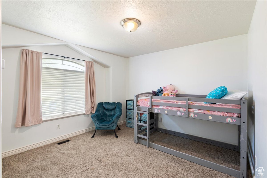 Carpeted bedroom featuring baseboards and a textured ceiling