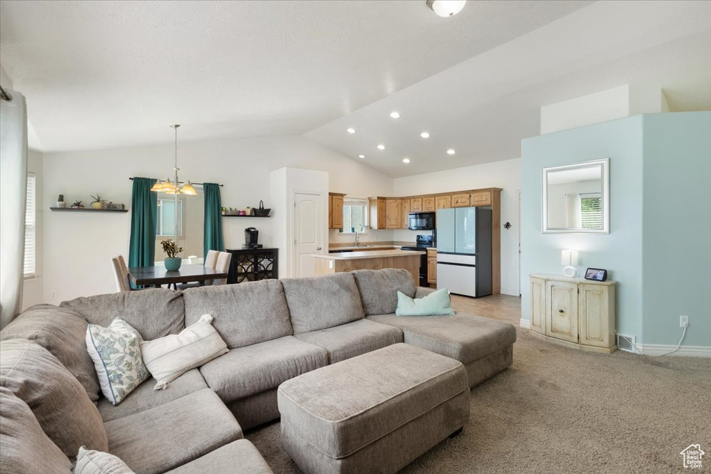 Living room featuring a chandelier, vaulted ceiling, plenty of natural light, recessed lighting, and light colored carpet