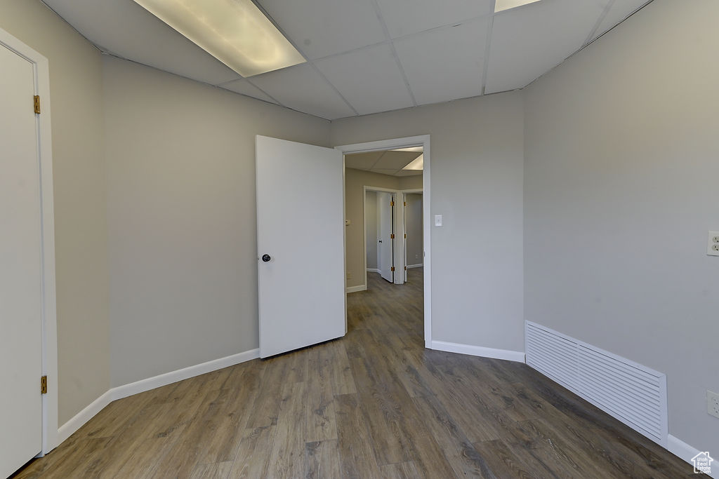 Unfurnished room featuring wood finished floors and a drop ceiling