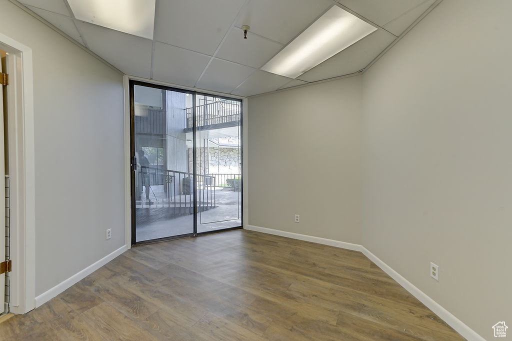 Unfurnished room featuring floor to ceiling windows, wood finished floors, and a drop ceiling