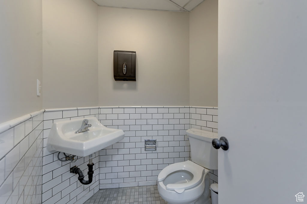 Half bathroom featuring tile walls, wainscoting, and tile patterned flooring