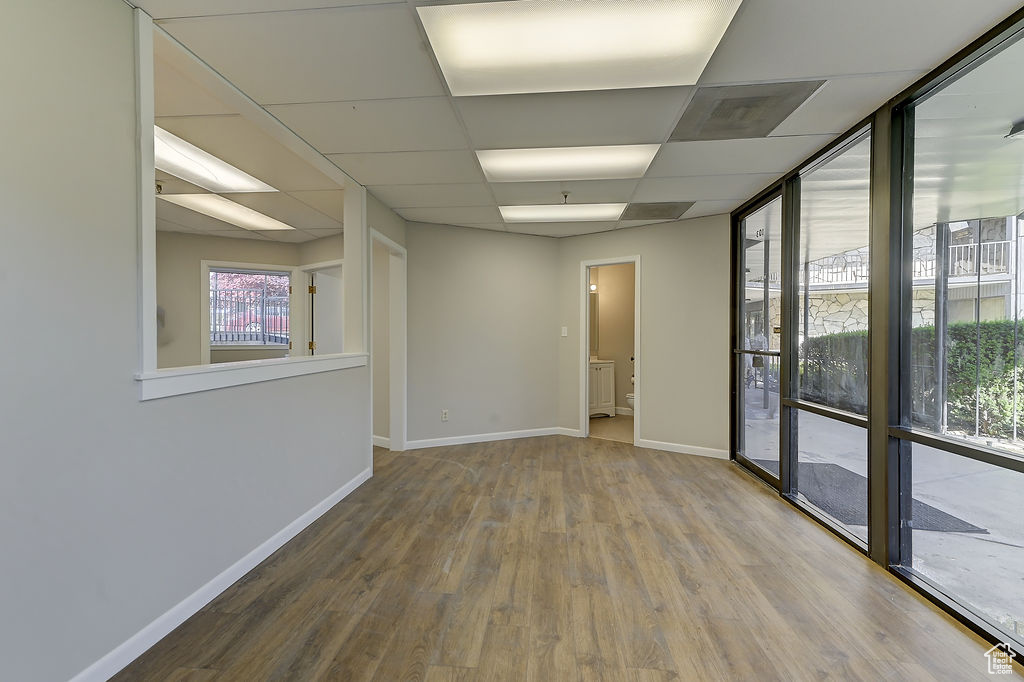 Spare room featuring wood finished floors, a drop ceiling, and expansive windows