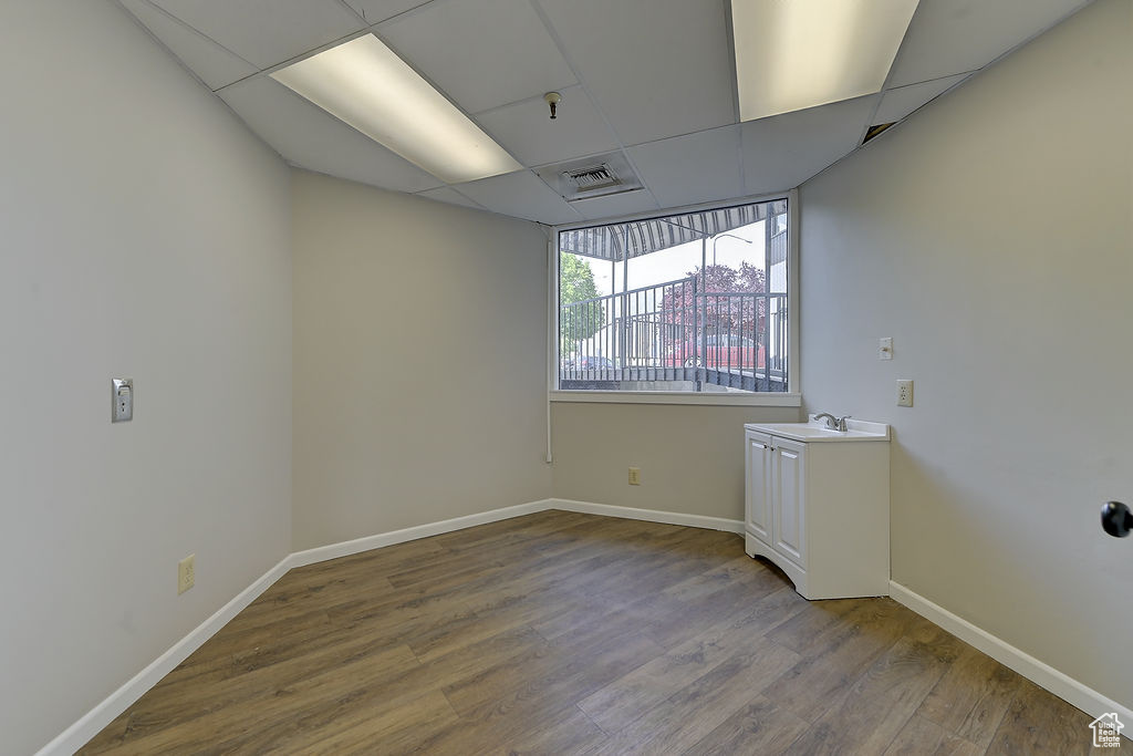 Empty room with wood finished floors, a paneled ceiling, and a pendent fire sprinkler