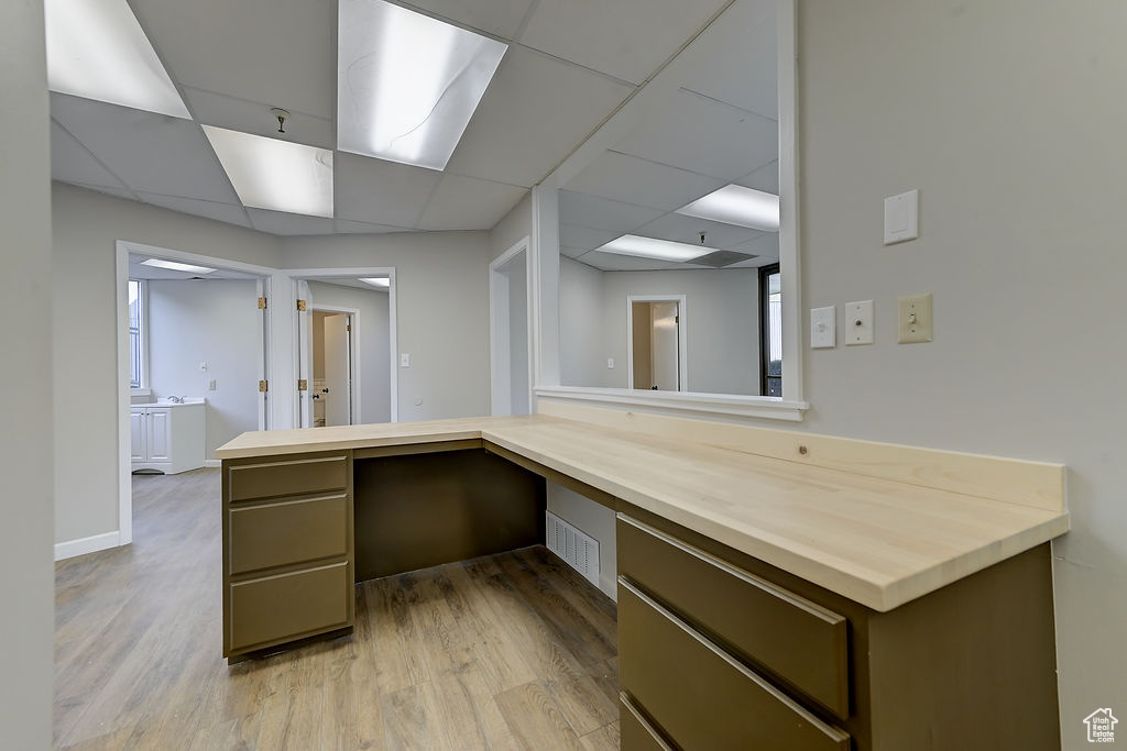 Unfurnished office featuring built in study area, a paneled ceiling, and light wood-style flooring