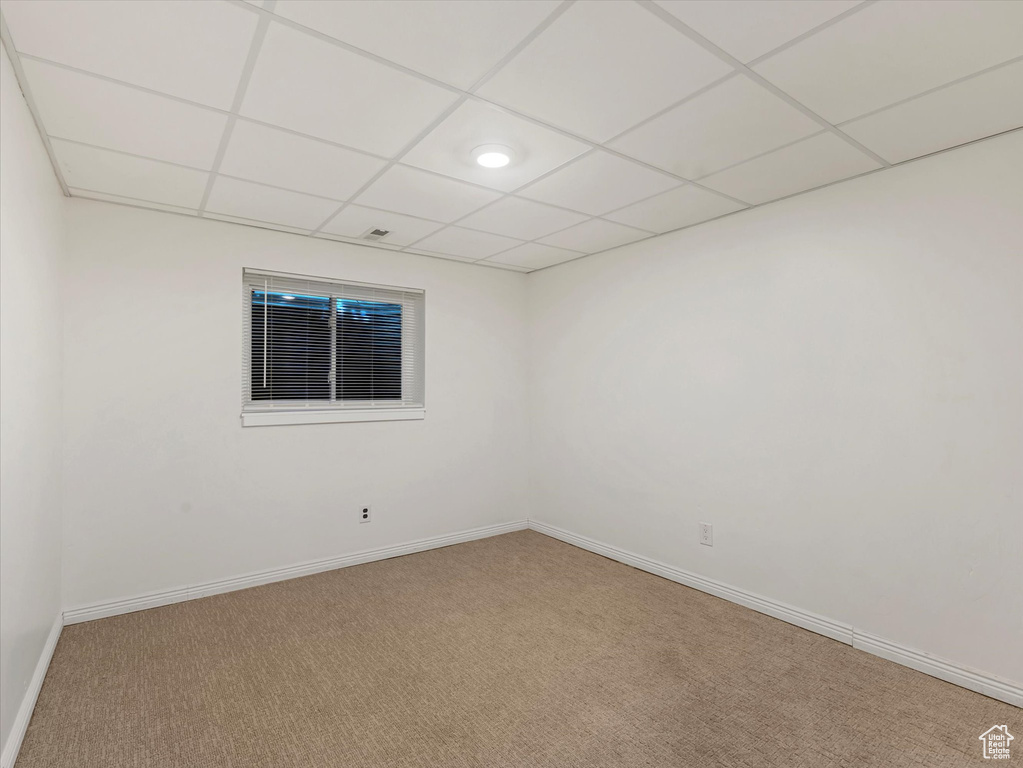 Carpeted spare room with baseboards and a drop ceiling