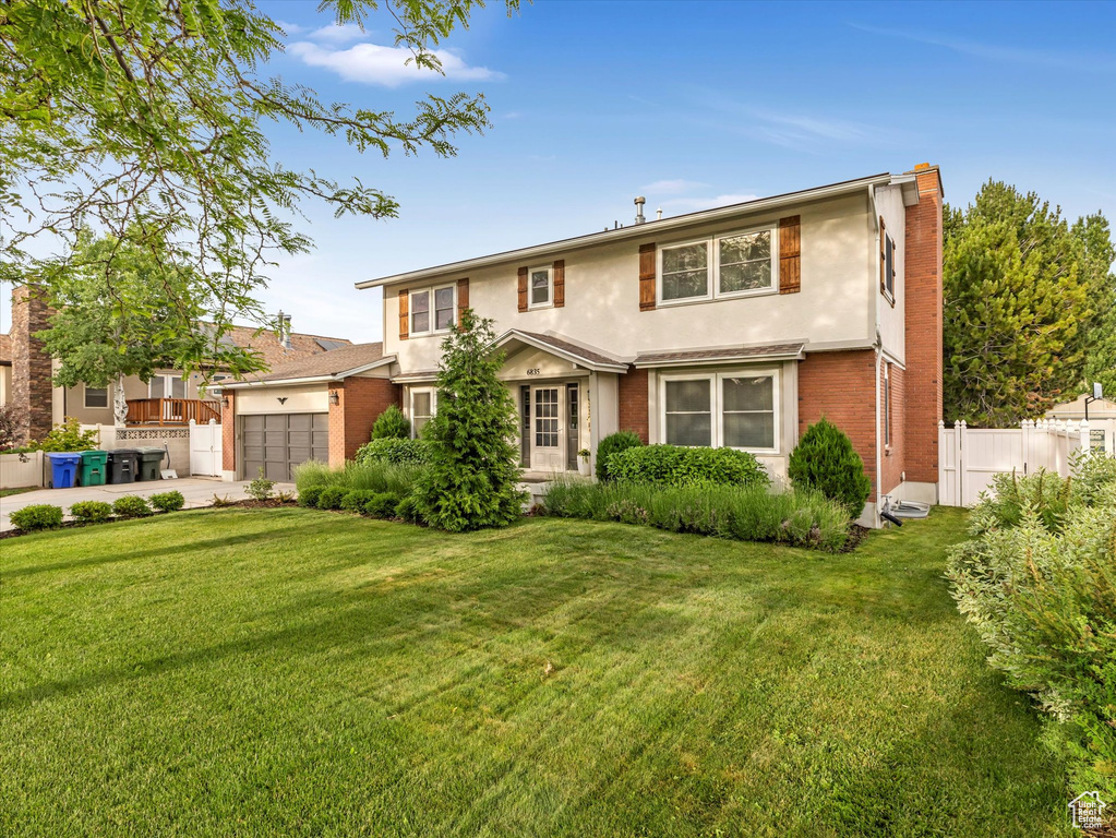 Traditional-style house with a garage, stucco siding, driveway, brick siding, and a chimney