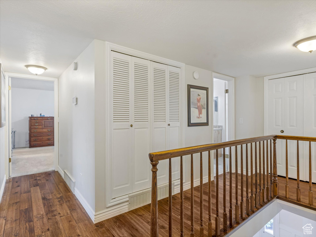 Corridor featuring dark wood-style floors and an upstairs landing