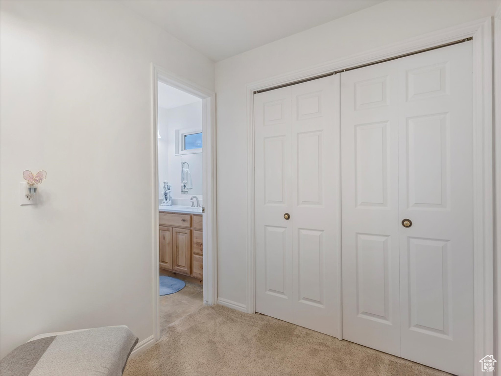 Bedroom featuring light colored carpet, a closet, and connected bathroom