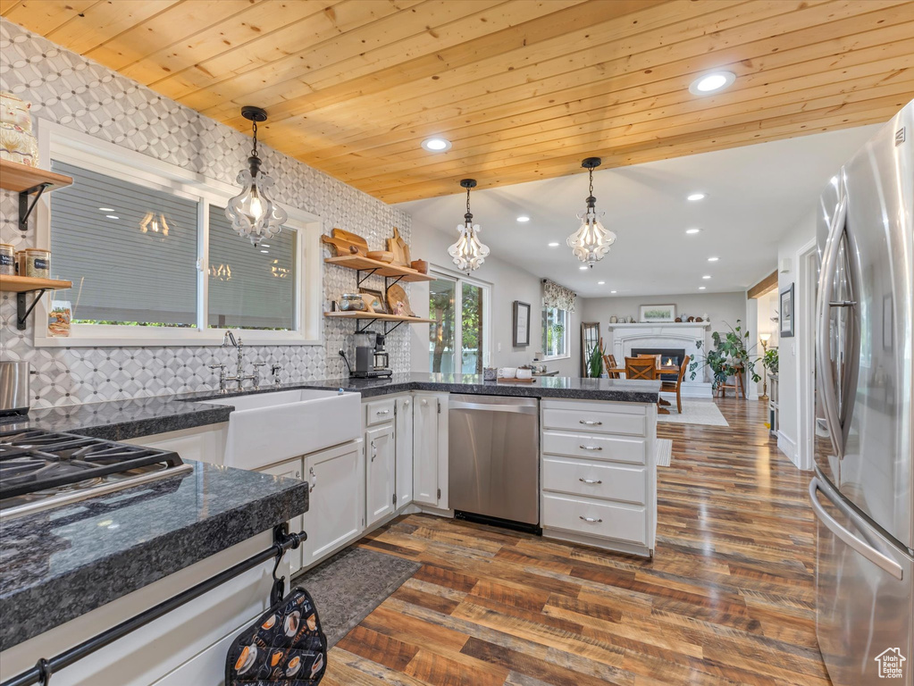 Kitchen with stainless steel appliances, open shelves, a peninsula, dark wood-type flooring, and backsplash