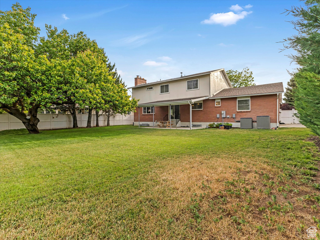 Rear view of property with a patio area, brick siding, a fenced backyard, and a chimney