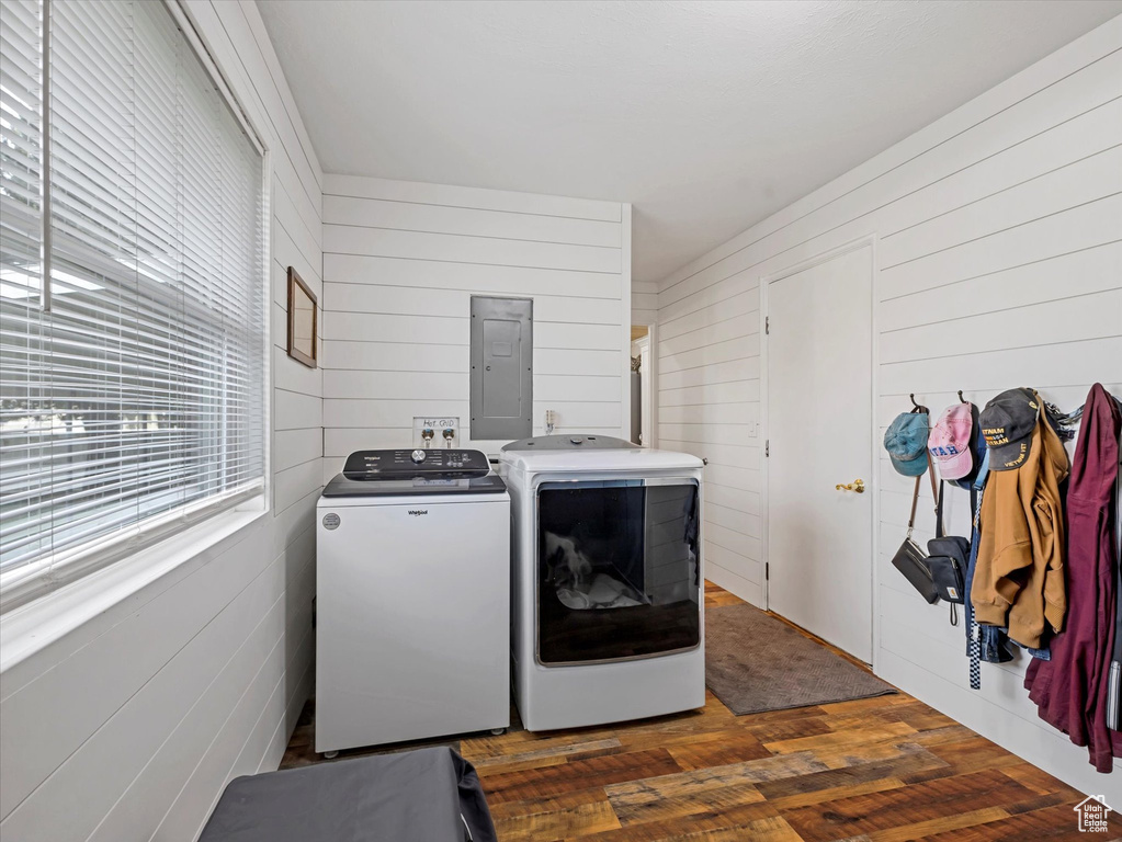 Laundry room featuring independent washer and dryer, electric panel, dark wood-style floors, and wooden walls