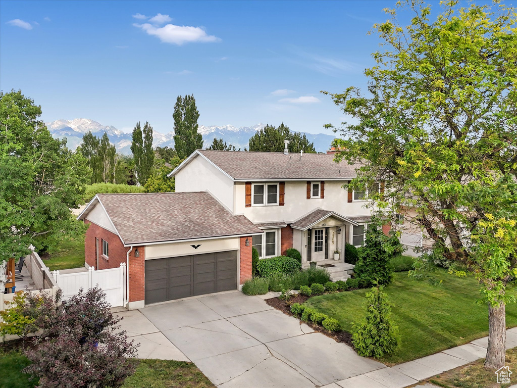 Traditional-style home featuring brick siding, a garage, driveway, roof with shingles, and stucco siding