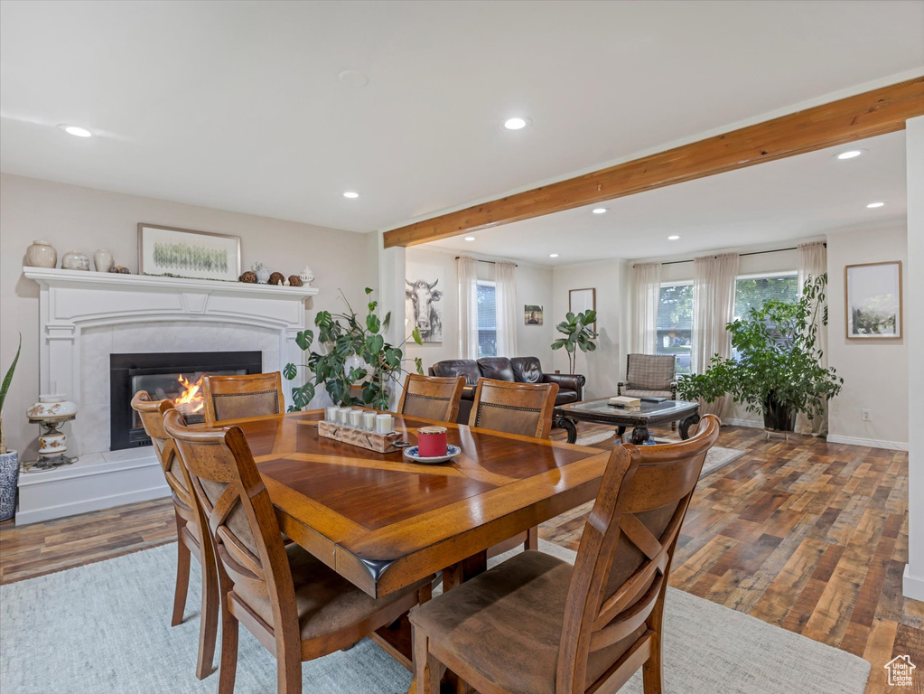 Dining room featuring wood finished floors, recessed lighting, a glass covered fireplace, and beamed ceiling