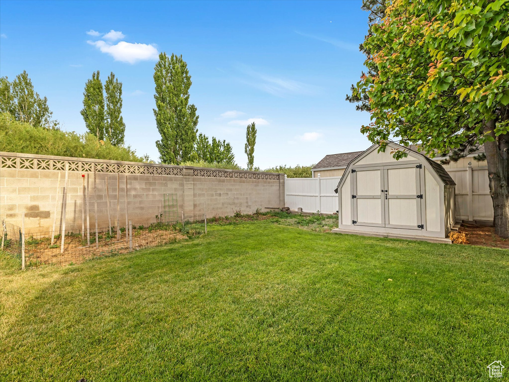 Fenced backyard featuring a storage unit