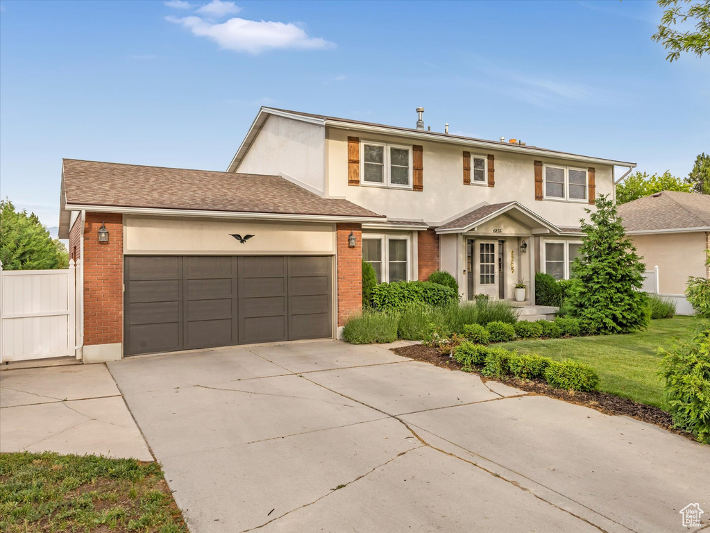 Traditional home with a garage, stucco siding, concrete driveway, and brick siding