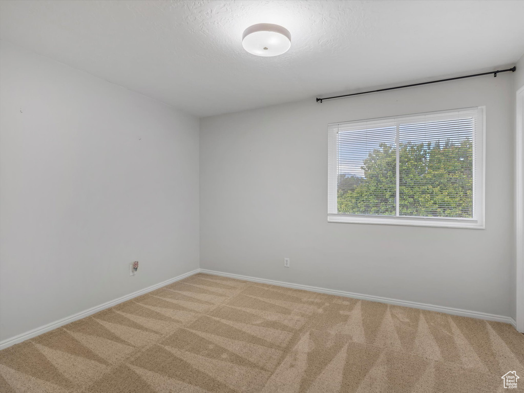 Spare room with light carpet and baseboards