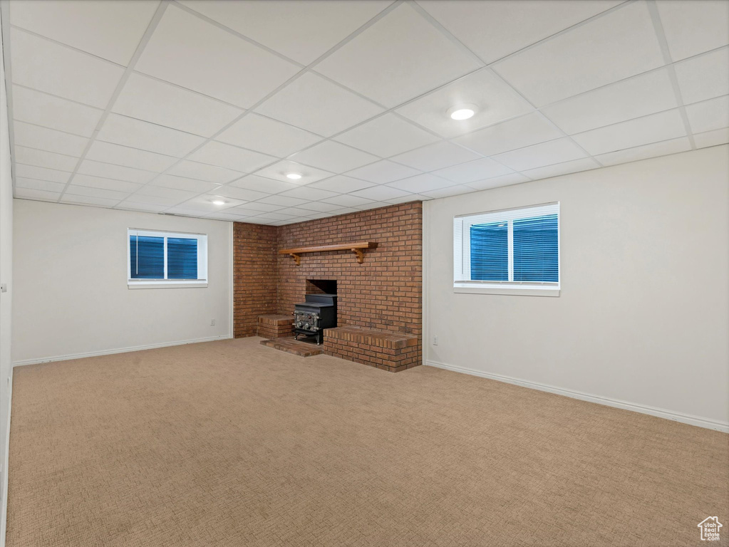 Unfurnished living room featuring a wood stove, carpet floors, a paneled ceiling, and recessed lighting