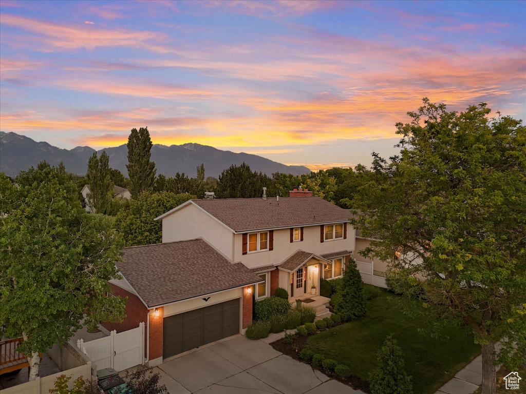 Traditional-style home with driveway, an attached garage, a mountain view, a chimney, and stucco siding