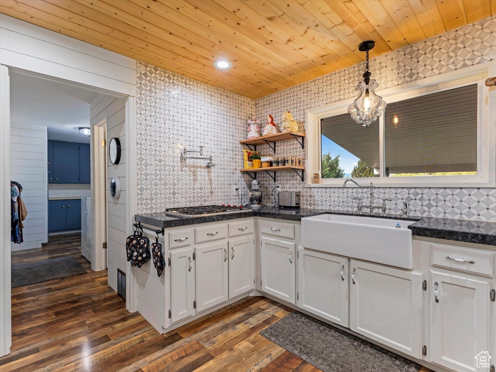 Kitchen featuring stainless steel gas cooktop, white cabinetry, dark wood-type flooring, decorative light fixtures, and wood ceiling