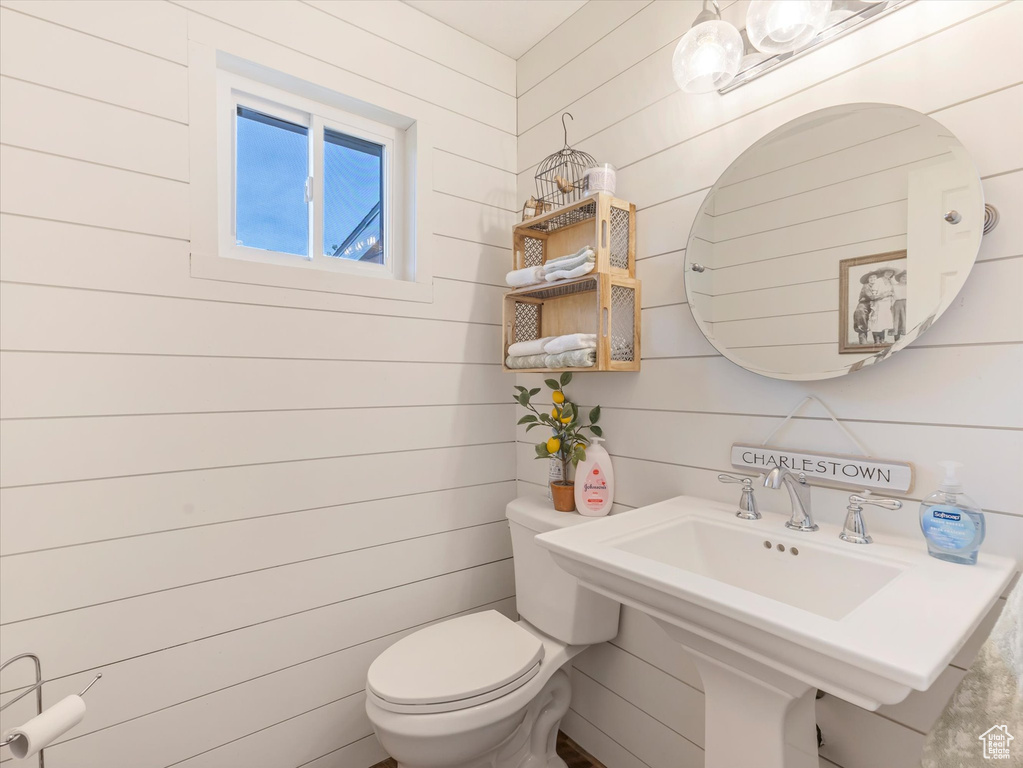 Half bathroom with toilet and wooden walls