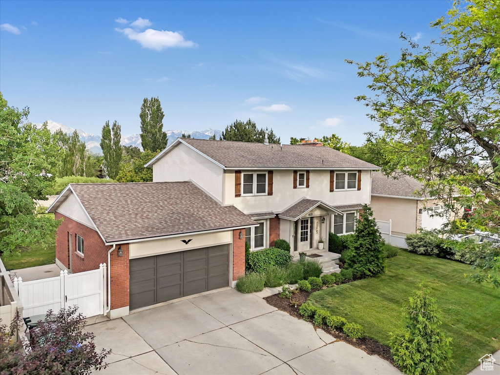 Traditional-style house with driveway, an attached garage, stucco siding, a shingled roof, and brick siding