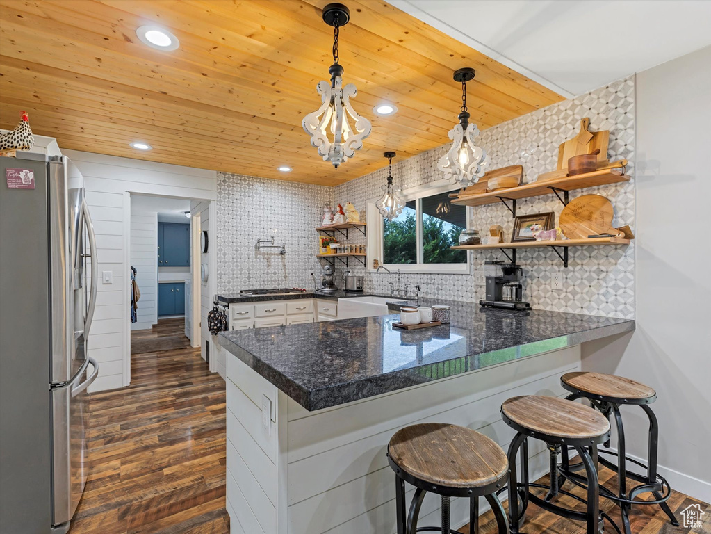 Kitchen with stainless steel appliances, open shelves, a peninsula, backsplash, and dark wood-style flooring