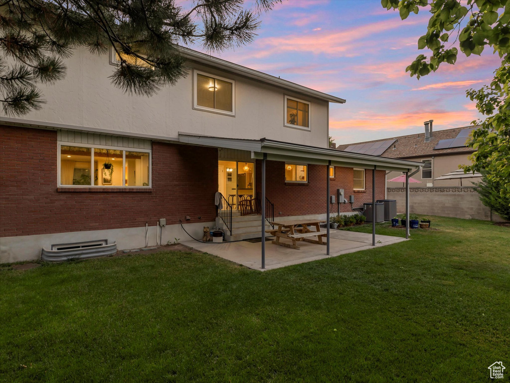 Back of house at dusk with a patio area and brick siding