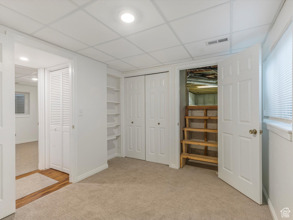 Unfurnished bedroom with light carpet and a drop ceiling
