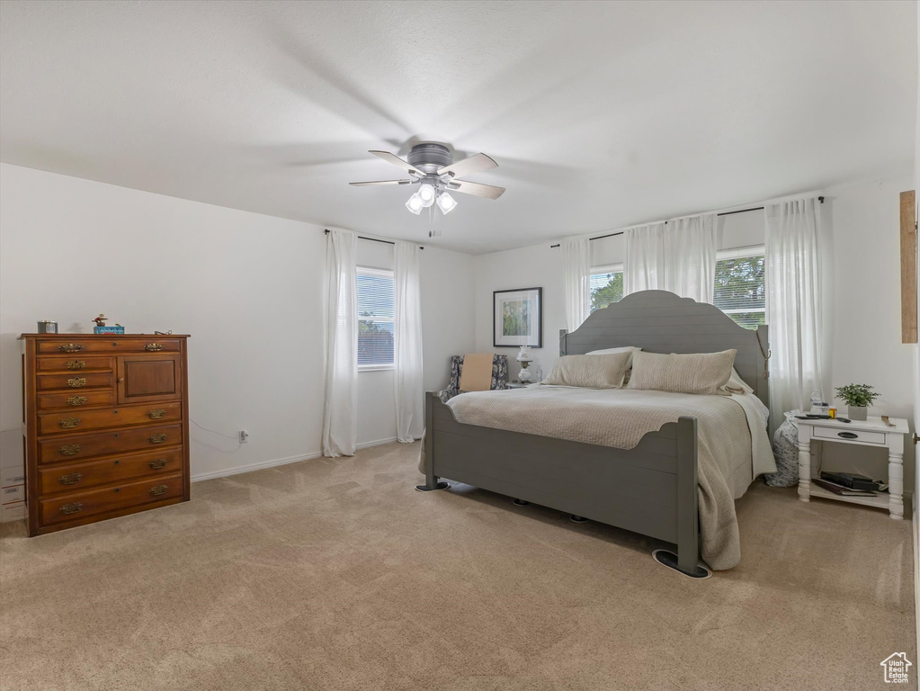 Bedroom with multiple windows, light carpet, and a ceiling fan
