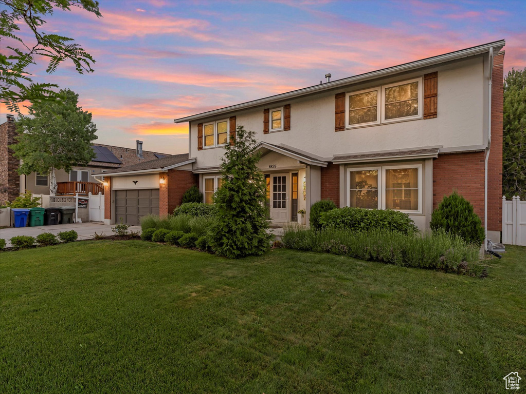 Traditional home with an attached garage, brick siding, stucco siding, and driveway