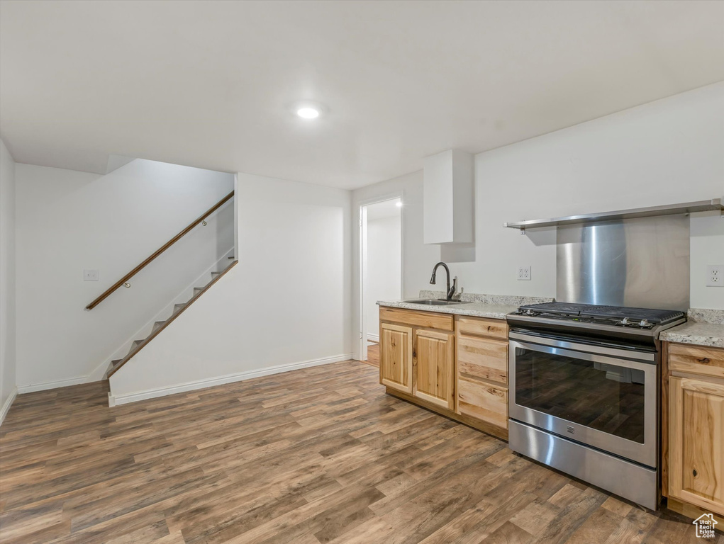 Kitchen featuring stainless steel range oven, wood finished floors, light brown cabinets, recessed lighting, and light stone countertops