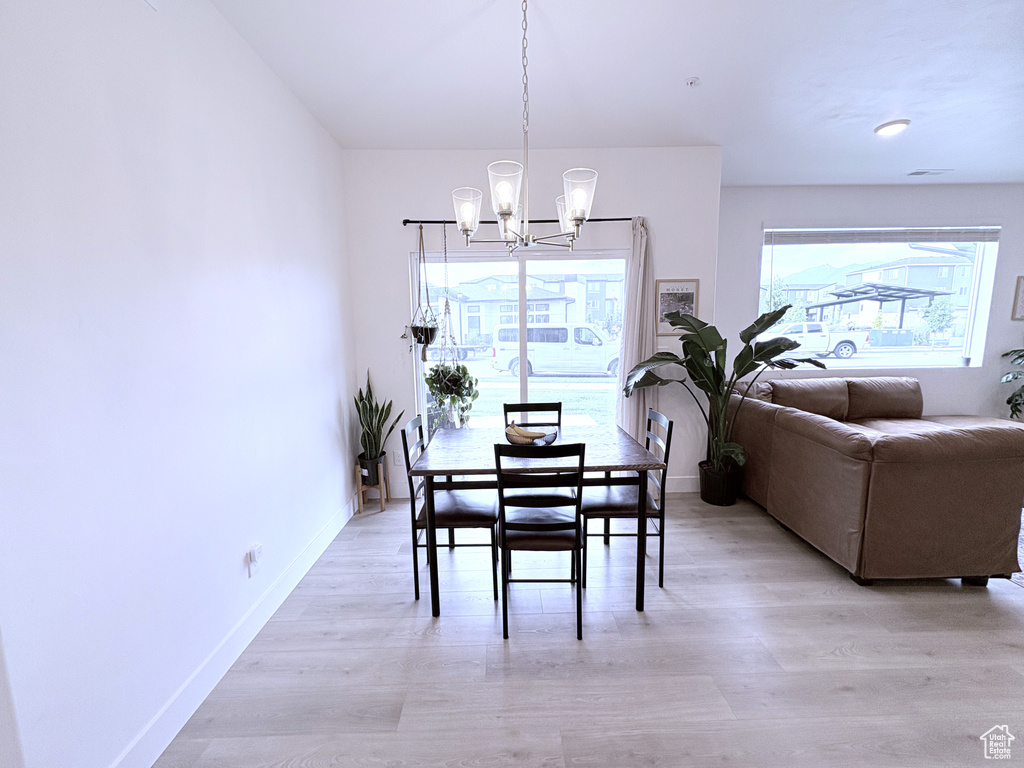 Dining space with a chandelier, plenty of natural light, and light wood-style flooring