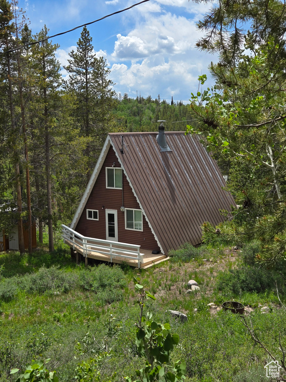 View of home's exterior with a deck and a view of trees