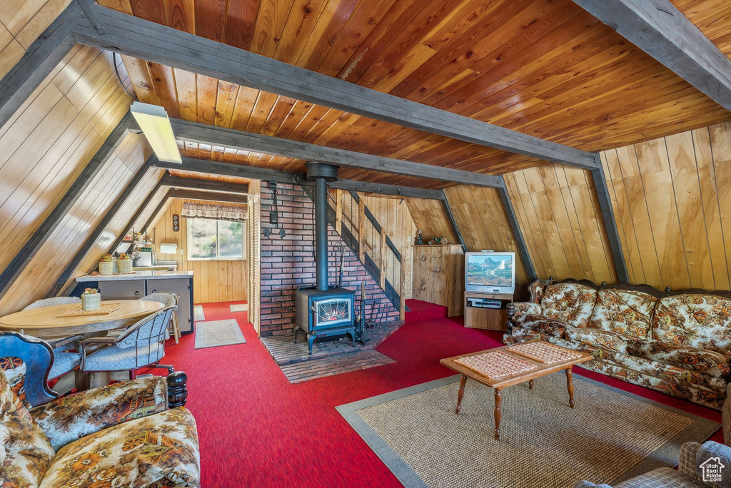Carpeted living room with a wood stove, wooden ceiling, and wooden walls
