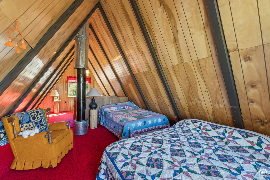 Bedroom with carpet, wood walls, and vaulted ceiling