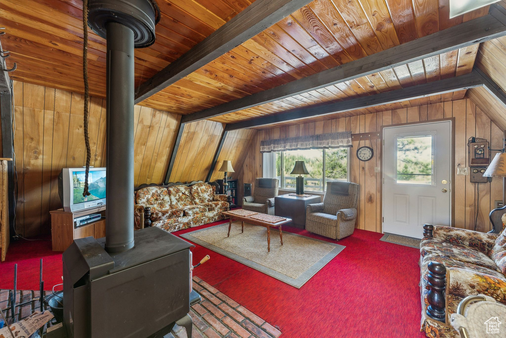 Living area featuring a wood stove, wooden walls, a wood ceiling with exposed beams, and carpet floors