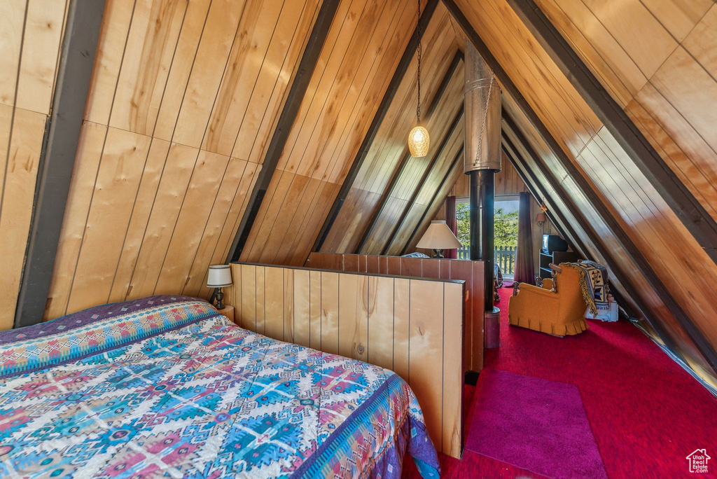 Bedroom featuring carpet flooring, wood walls, and lofted ceiling