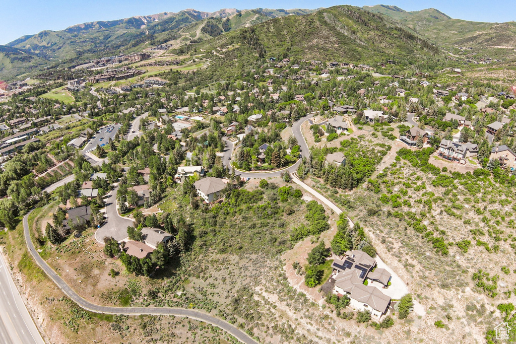 Aerial view of property and surrounding area featuring mountains and nearby suburban area